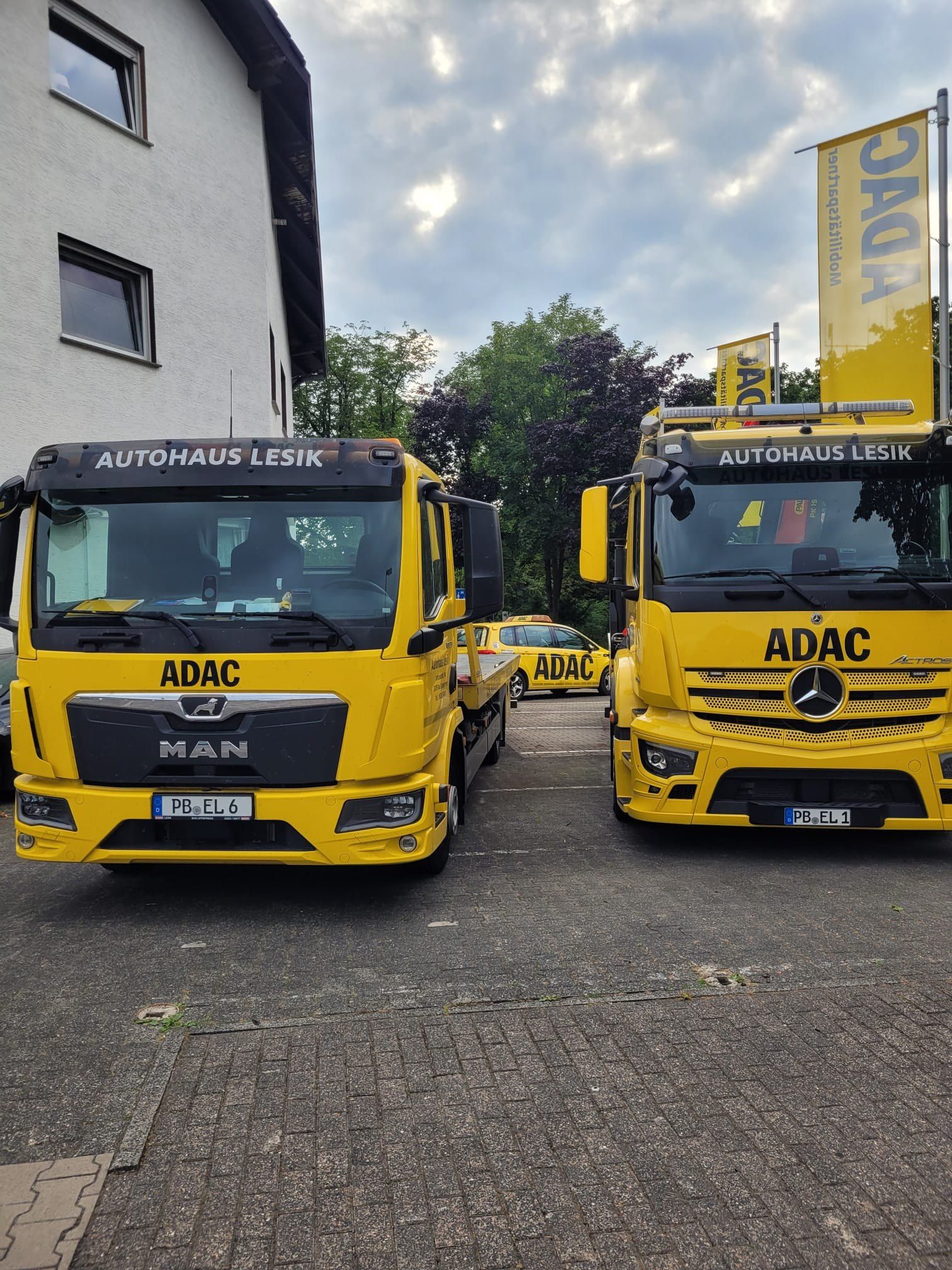 Zwei Abschleppwagen vor den ADAC-Fahnen am Hof